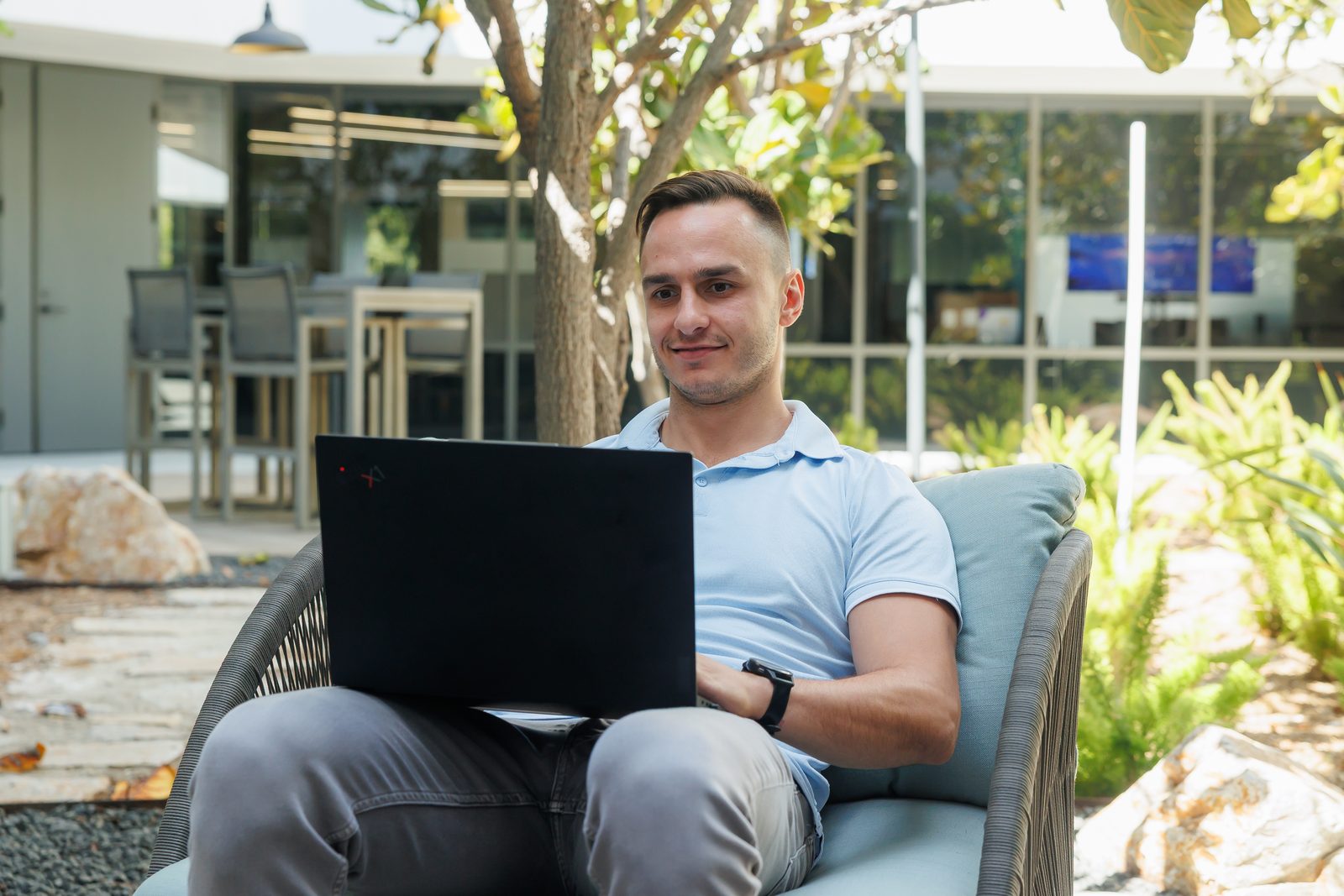 Corey Pecoraro sitting outside with his laptop, looking up from the screen