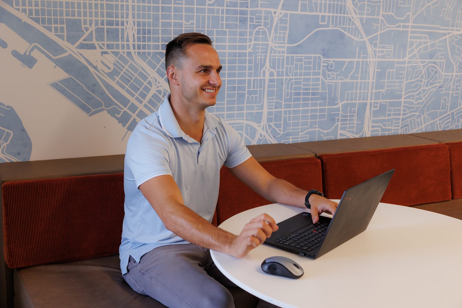 Corey Pecoraro working at a laptop at a round table, smiling off camera